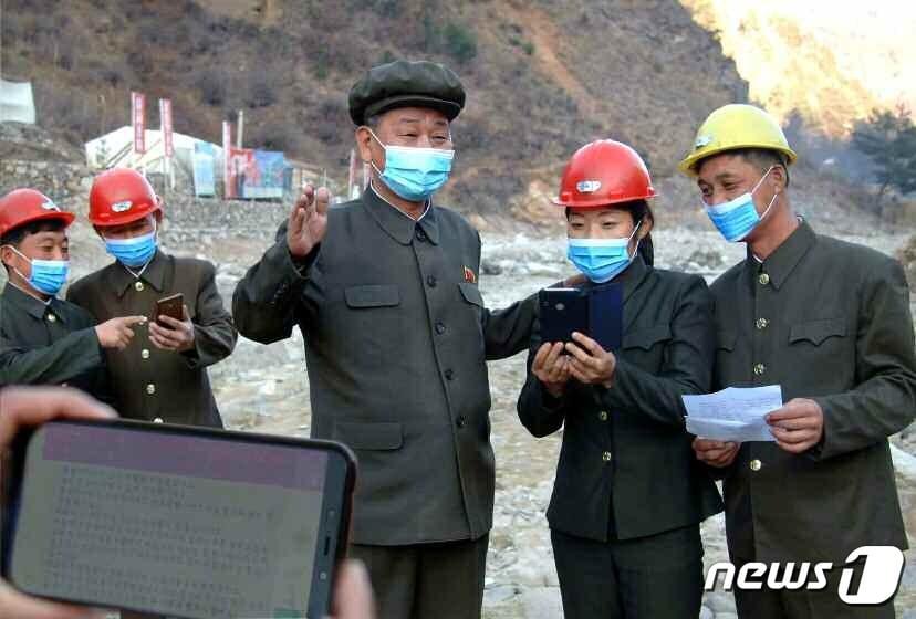 A division of party members in North Korea's capital reading letters of encouragement on their cell phones / Rodong Sinmun