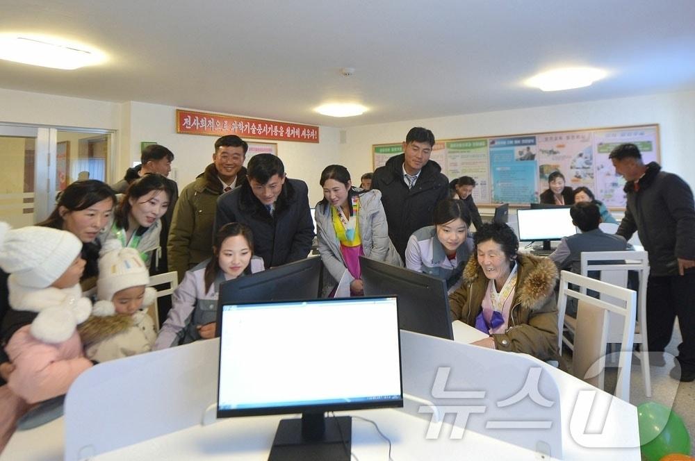North Korean residents gathered around a computer / Rodong Sinmun